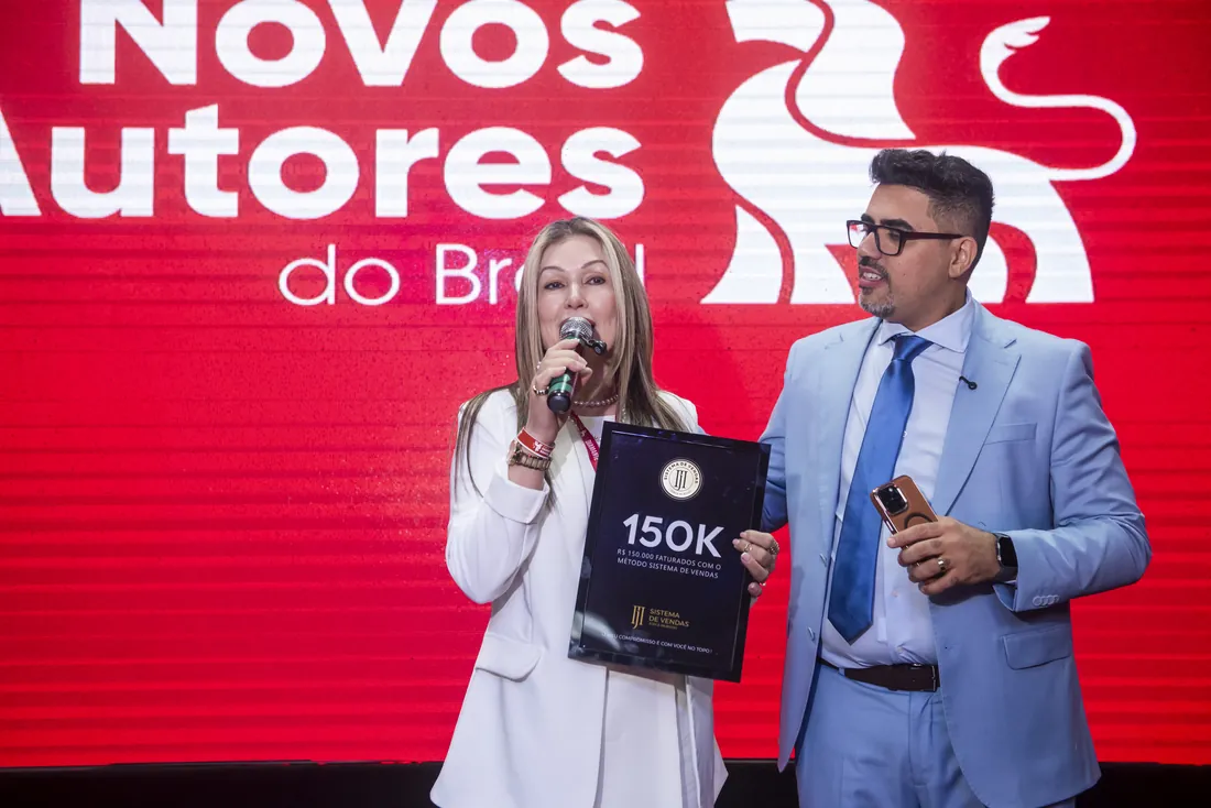 Mentorada recebendo a placa 150K no palco do evento