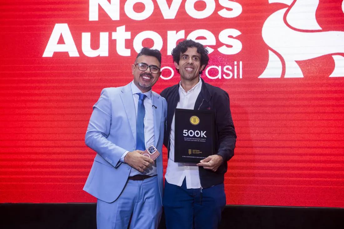 Mentorado recebendo a placa 500K no palco do evento