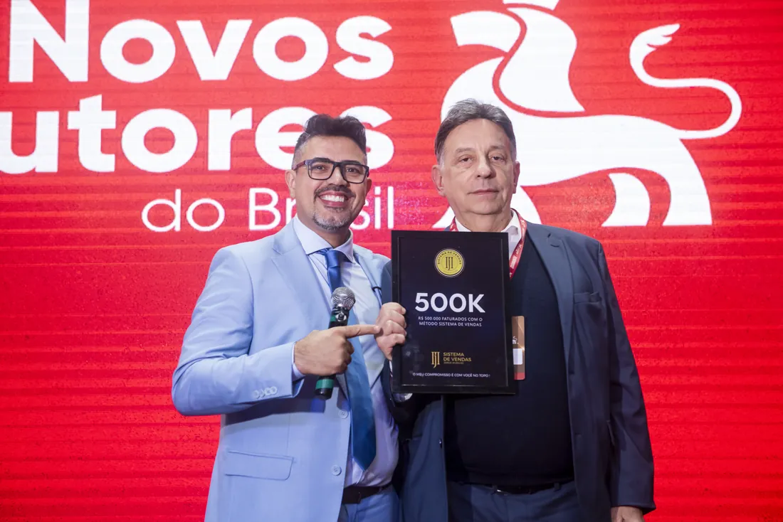 Mentorado recebendo outra placa 500K no palco do evento