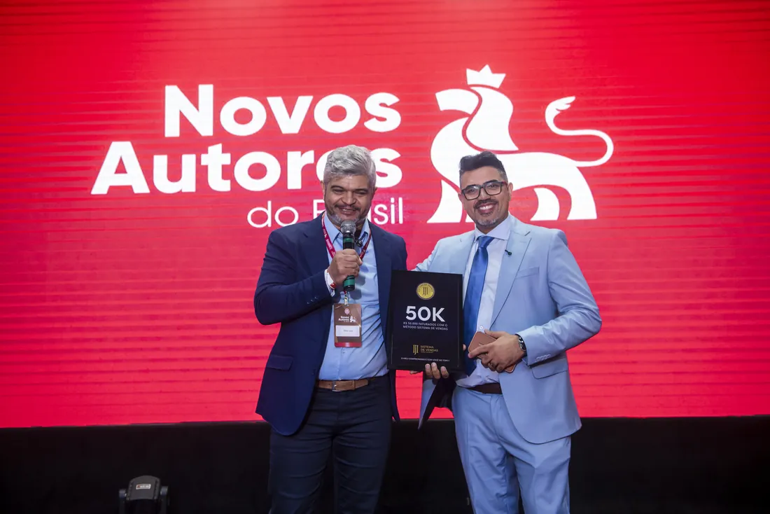 Mentorado recebendo a placa 50K no palco do evento